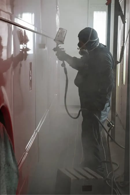 Painter applying BASF & PPG certified paint on a motorcoach